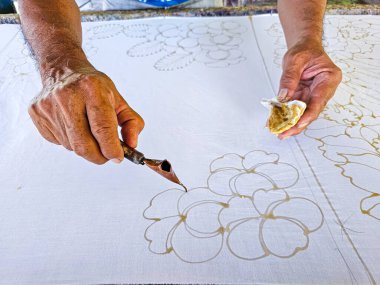 Tayland 'da kumaşa el yazması desenler çizerek batik yapmak.