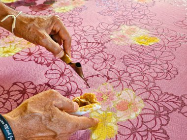 Tayland 'da kumaşa el yazması desenler çizerek batik yapmak.