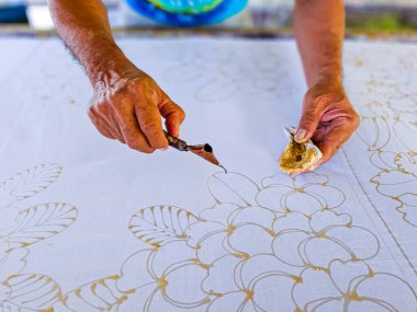 Tayland 'da kumaşa el yazması desenler çizerek batik yapmak.