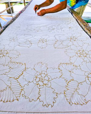 Tayland 'da kumaşa el yazması desenler çizerek batik yapmak.