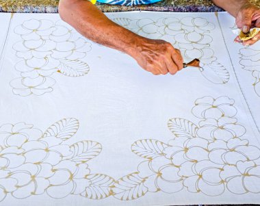 Tayland 'da kumaşa el yazması desenler çizerek batik yapmak.