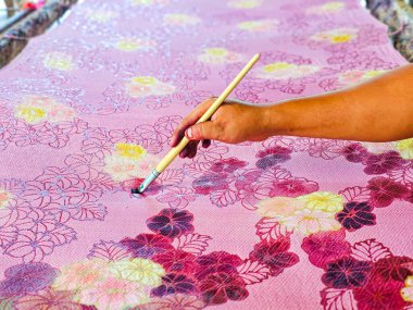 Tayland 'da kumaşa el yazması desenler çizerek batik yapmak.