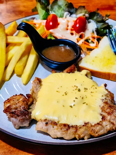 Chicken Steak with Sauce Served with french fries, salad and bread on a plate.