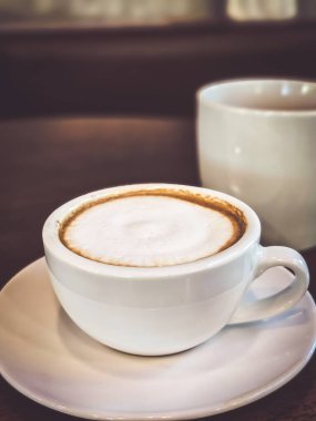 Sıcak bir kapuçino kahvesi, sıcak bir atmosferde masanın üzerine konmuş, metin için yer var..