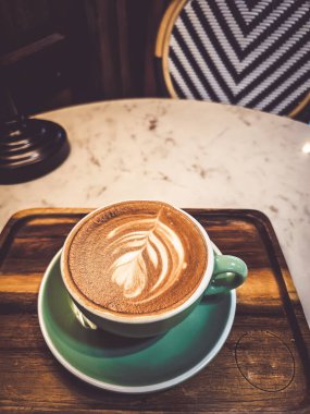 Sıcak bir kapuçino kahvesi, sıcak bir atmosferde masanın üzerine konmuş, metin için yer var..