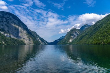 Güneşli bir yaz gününde Berchtesgaden Ulusal Parkı 'nda arka planda Bavyera Alpleri' nin bulunduğu Konigssee Gölü 'nün güzel manzarası mavi gökyüzü ve bulutlu, Schoenau, Bavyera, Almanya