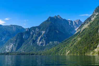 Güneşli bir yaz gününde Berchtesgaden Ulusal Parkı 'nda arka planda Bavyera Alpleri' nin bulunduğu Konigssee Gölü 'nün güzel manzarası mavi gökyüzü ve bulutlu, Schoenau, Bavyera, Almanya