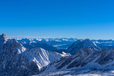 Güneşli bir günde, Zugspitzplatt 'tan Avusturya Alpleri' nin kar manzaralı muhteşem manzarası. Kışın mavi gökyüzü ve bulutlu, Garmisch-Partenkirchen, Bavyera, Almanya