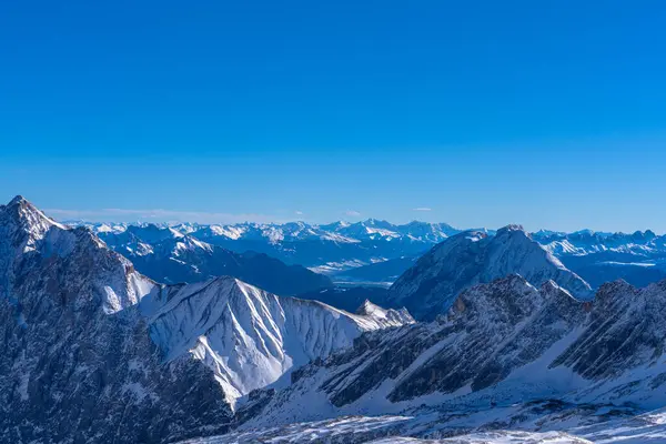 Güneşli bir günde, Zugspitzplatt 'tan Avusturya Alpleri' nin kar manzaralı muhteşem manzarası. Kışın mavi gökyüzü ve bulutlu, Garmisch-Partenkirchen, Bavyera, Almanya