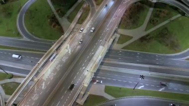 Polonya 'nın Varşova şehrinin dışındaki köprüleri ve viyadikleriyle arabaları ve ışık şeritlerini gösteren bir otoyoldaki gece uçağının görüntüsü. Kamerayı ileri alıyorum..