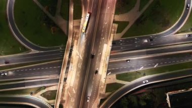 Varşova 'nın banliyölerinde Polonya' nın kırsal kesimlerinde geceleri yoğun bir otoyol boyunca giden uzun mesafeli yarı karavanların insansız hava aracı görüntüleri. Geceleri otobanın havadan görüntüsü, köprüleri olan arabalar ve kamyonlar yolda.