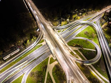 Hava görüntüsü kavşağı kavşağı çevre yolu ve otoyol otoyolları ve hareket halindeki farlı araçlar gece hava manzaralı Varşova 'da şehrin arka planını aydınlatan araçlar.