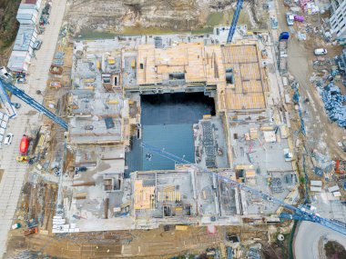 Vinçli ve binalı inşaat alanının havadan görüntüsü. Büyük inşaat ve mimarinin en üst görünümü.