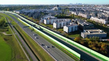 Varşova / Polonya şehrinin karayolu trafik evleri ve gökdelenlerinin havadan görünüşü. Şehir manzarası, Wilanow bölgesi, güneşli bir yaz gününde kalabalık sokaklar ve parklar. 4K İHA 'da vuruldu.