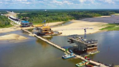 Nehir üzerinde yeni bir köprü inşa ediliyor. Köprüden geçen kule vinçleri. Kazıcılar ve yükleyiciler köprüler ve yollar üzerinde çalışıyor. Varşova. Polonya