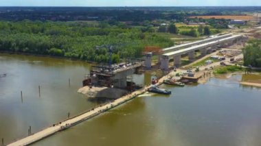 Nehir üzerinde yeni bir köprü inşa ediliyor. Köprüden geçen kule vinçleri. Kazıcılar ve yükleyiciler köprüler ve yollar üzerinde çalışıyor. Varşova. Polonya