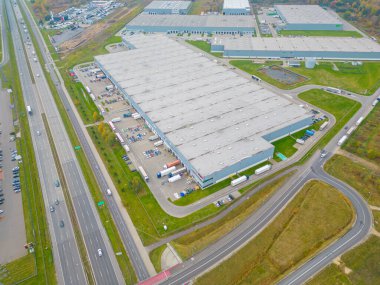 Gün batımında yükleme / boşaltma malları için rampalarda bekleyen bir lojistik parkı, merkez ve kargo karavanıyla dolu bir sürü tırın hava görüntüsü..