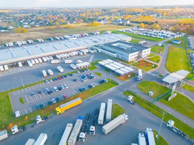 Malzeme deposunun havadan görüntüsü. Sanayi bölgesindeki lojistik merkezi yukarıdan. Lojistik merkezde yüklenen kamyonların hava görüntüsü. İnsansız hava aracından görüntüle.