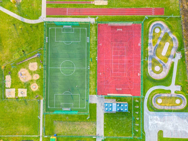 Okul spor sahasında futbol stadyumu, koşu pistleri. Basketbol, voleybol, tenis kortları. Hava fotoğrafı, üst görünüm.