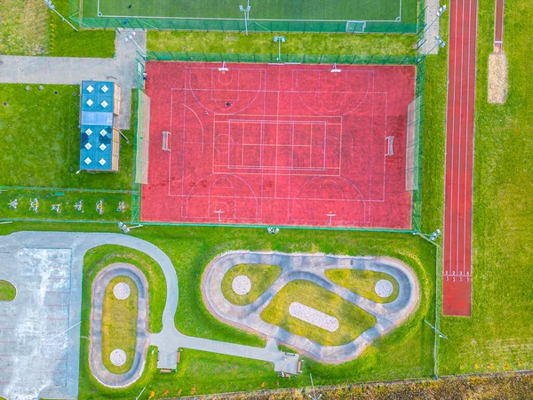 Okul spor sahasında futbol stadyumu, koşu pistleri. Basketbol, voleybol, tenis kortları. Hava fotoğrafı, üst görünüm.