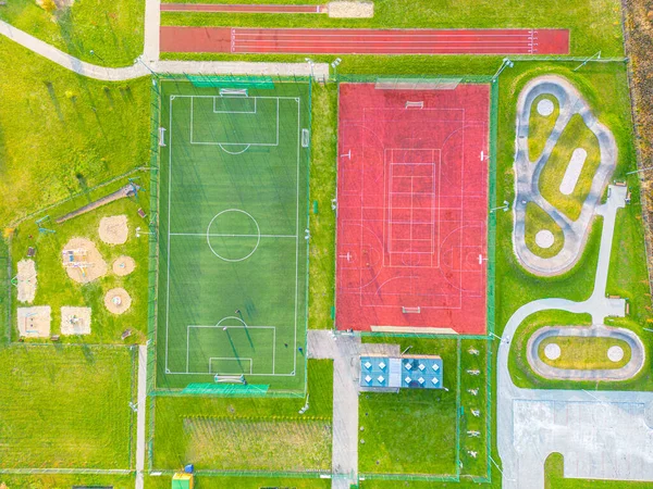 Okul spor sahasında futbol stadyumu, koşu pistleri. Basketbol, voleybol, tenis kortları. Hava fotoğrafı, üst görünüm.