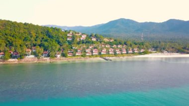 4K Aerial Front View of Surin Beach, Phuket. Beach, sea, sand and palms. Drone view of a beautiful white tropical sand beach on a summer day. Top view empty and clean beach. Phuket, Thailand.