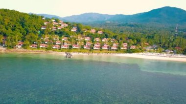 4K Aerial Front View of Surin Beach, Phuket. Beach, sea, sand and palms. Drone view of a beautiful white tropical sand beach on a summer day. Top view empty and clean beach. Phuket, Thailand.