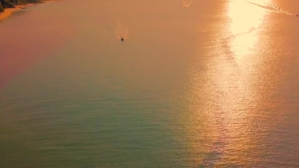 海の上の風景夕日 空中ビュー 海岸線の近くに喜びのボートと水の中に反映オレンジのパスを持つ素晴らしい夕日 水平線の低いパノラマビューの太陽は水に歩道とグレアを残します — ストック動画