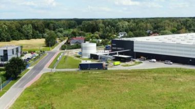 Semi truck with cargo trailer is travelling along a parking lot of a warehouse in the logistics park. A lot of semi-trailers trucks stands at warehouses ramps for load/unload goods. Aerial view