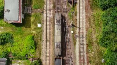 Railway cargo train wagon rides on railroad. Transportation and delivery of cargo in containers. Aerial view over train riding near river and coal power plant.