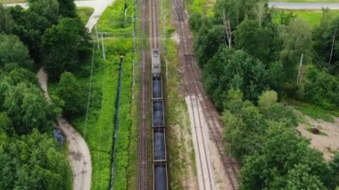 Railway cargo train wagon rides on railroad. Transportation and delivery of cargo in containers. Aerial view over train riding near river and coal power plant.