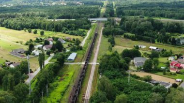 Railway cargo train wagon rides on railroad. Transportation and delivery of cargo in containers. Aerial view over train riding near river and coal power plant.
