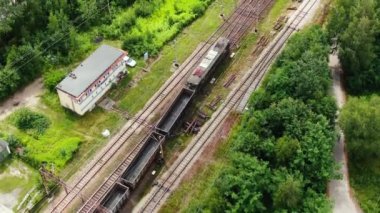 Railway cargo train wagon rides on railroad. Transportation and delivery of cargo in containers. Aerial view over train riding near river and coal power plant.