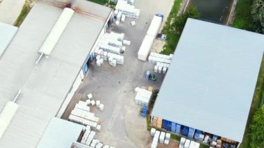 Aerial circling view of a logistics center with warehouse, loading hub with many semi-trailers trucks load/unload goods at sunset