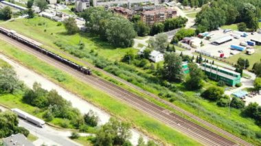 Railway cargo train wagon rides on railroad. Transportation and delivery of cargo in containers. Aerial view over train riding near river and coal power plant.