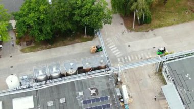 Aerial circling view of a logistics center with warehouse, loading hub with many semi-trailers trucks load/unload goods at sunset