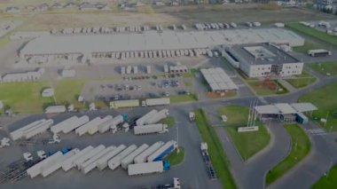 Deposu ve yükleme merkezi olan bir lojistik parkı. Gün batımında malları yüklemek ve boşaltmak için rampalarda bekleyen kargo römorklu yarı kamyonlar. Hava hiper hızı.