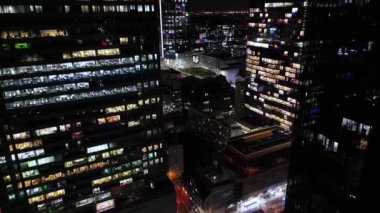Office buildings with lights in the city downtown. Drone aerial view. People working in office building in the night, building lights in the night . Economy business cityscape concept b-roll footage.