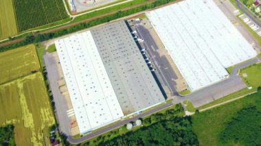Aerial view of a semi trucks with cargo trailers standing on warehouses ramps for loading/unloading goods on the big logistics park with loading hub