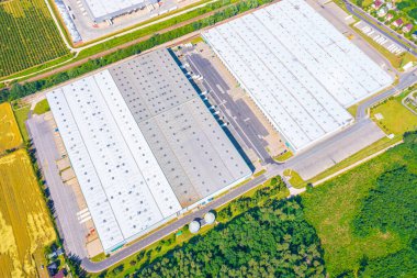 Gün batımında yükleme / boşaltma malları için rampalarda bekleyen depo, merkez ve kargo karavanıyla lojistik parkının hava görüntüsü. 