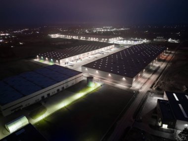 Gece vakti malzeme deposunun havadan görüntüsü. Sanayi bölgesindeki lojistik merkezi yukarıdan. Lojistik merkezde yüklenen kamyonların hava görüntüsü. İnsansız hava aracından görüntüle.