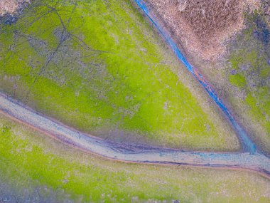 An aerial shot of the landscape with small lake surrounded by trees and field