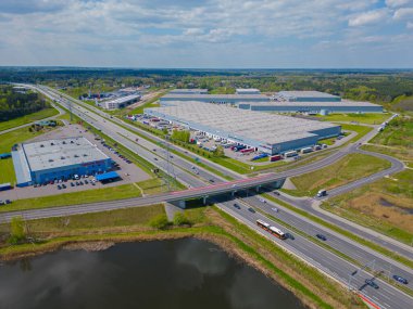 Gün batımında yükleme / boşaltma malları için rampalarda bekleyen depo, merkez ve kargo karavanıyla lojistik parkının hava görüntüsü.