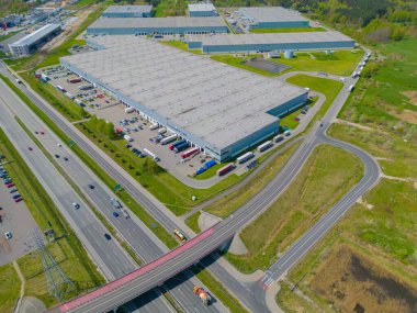 Gün batımında yükleme / boşaltma malları için rampalarda bekleyen depo, merkez ve kargo karavanıyla lojistik parkının hava görüntüsü.