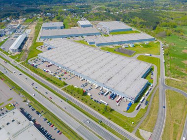 Gün batımında yükleme / boşaltma malları için rampalarda bekleyen depo, merkez ve kargo karavanıyla lojistik parkının hava görüntüsü.