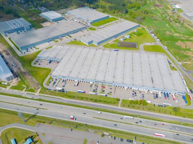 Gün batımında yükleme / boşaltma malları için rampalarda bekleyen depo, merkez ve kargo karavanıyla lojistik parkının hava görüntüsü.