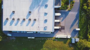 Malzeme deposunun havadan görüntüsü. Sanayi bölgesindeki lojistik merkezi yukarıdan. Lojistik merkezde yüklenen kamyonların hava görüntüsü. İnsansız hava aracından görüntüle.