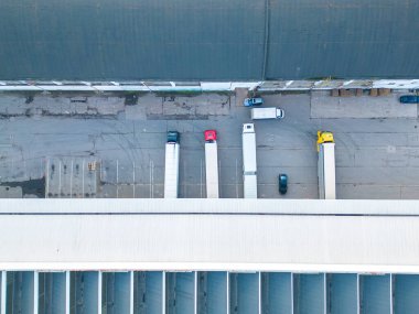 Malzeme deposunun havadan görüntüsü. Sanayi bölgesindeki lojistik merkezi yukarıdan. Lojistik merkezde yüklenen kamyonların hava görüntüsü. İnsansız hava aracından görüntüle.