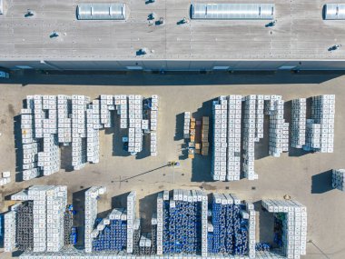 Malzeme deposunun havadan görüntüsü. Sanayi bölgesindeki lojistik merkezi yukarıdan. Lojistik merkezde yüklenen kamyonların hava görüntüsü. İnsansız hava aracından görüntüle.