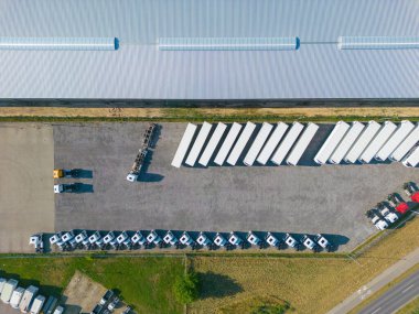 Gün batımında yükleme / boşaltma malları için rampalarda bekleyen depo, merkez ve kargo karavanıyla lojistik parkının hava görüntüsü.